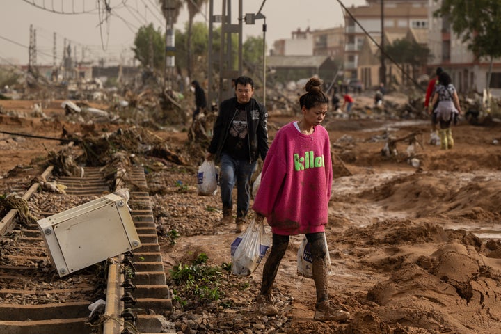 A woman walks along train tracks covered in debris after floods hit the Valencia region.