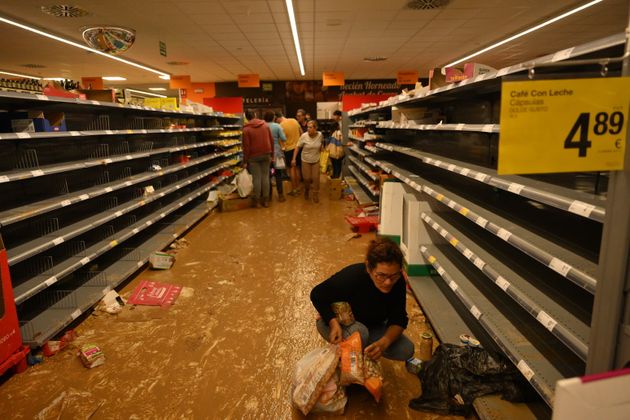 Άνθρωποι συλλέγουν αντικείμενα σε λασπωμένους διαδρόμους σε ένα σούπερ μάρκετ που υπέστη βανδαλισμό μετά από τις πλημμύρες που έπληξαν τον δήμο Paiporta της Βαλένθια της Ισπανίας. 