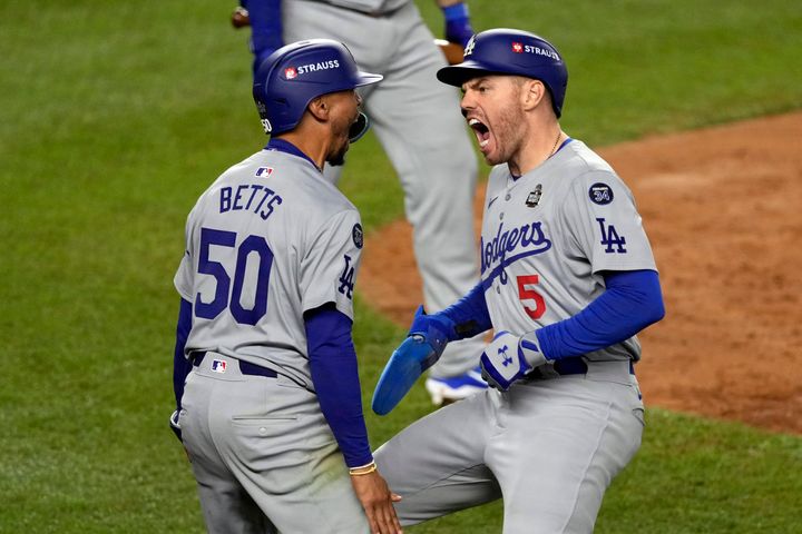 Los Angeles Dodgers' Mookie Betts (50) and Freddie Freeman (5) celebrate after scoring against the New York Yankees during the fifth inning in Game 5 of the baseball World Series, Wednesday, Oct. 30, 2024, in New York. (AP Photo/Seth Wenig)