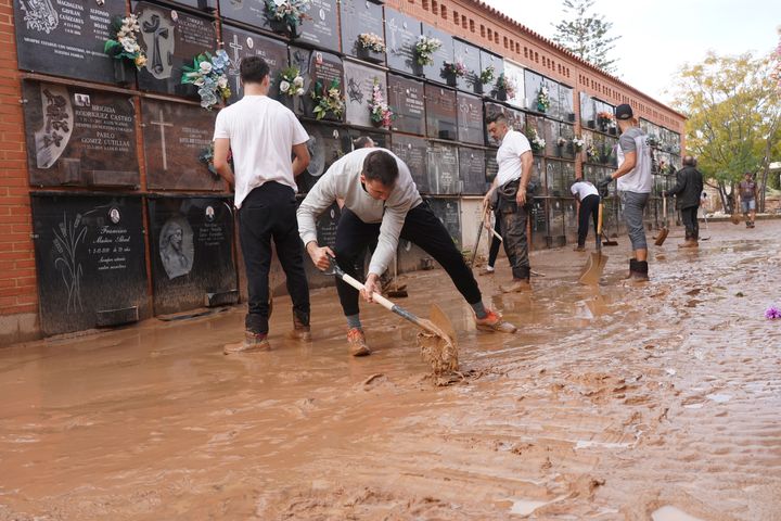 People clear away mud from inside a flood-damaged cemetery on the outskirts of Valencia, Spain.