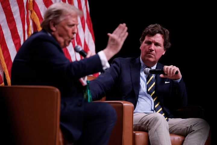 Former President Donald Trump, the 2024 Republican presidential nominee, sits to the left of conservative pundit Tucker Carlson at an event on Friday, Oct. 31, 2024, in Phoenix, Arizona.