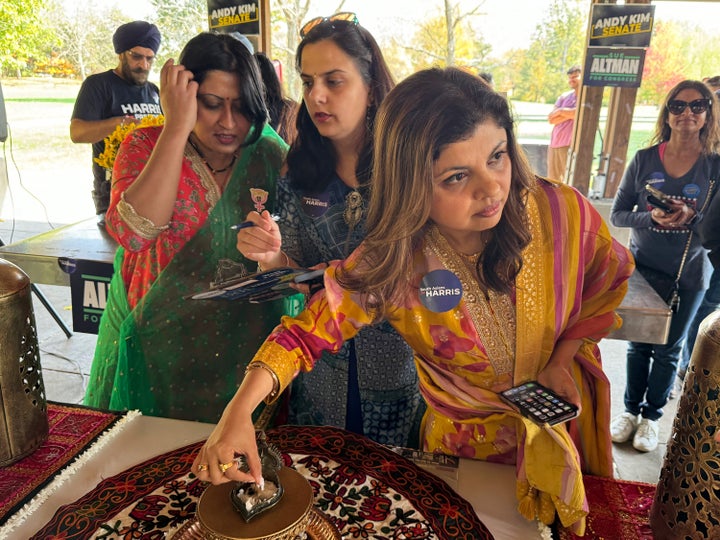 Radhika Sharma, right, prepares the diya alongside fellow co-chair of New Jersey Democrats' South Asian American Caucus, Parul Khemka, center, and Harini Krishnan, the California-based national organizing chair for South Asians for Harris.