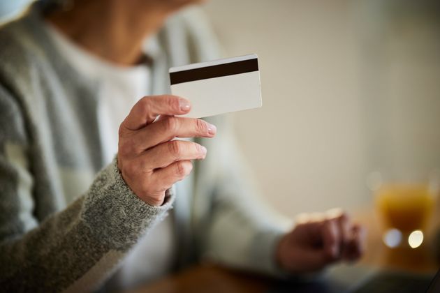 Close up of unrecognizable senior woman using credit card at home.