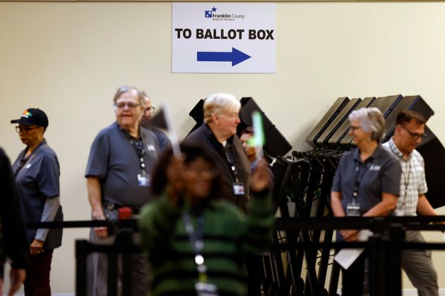 Poll workers wait to escort voters to the polling booths during the first day of in person early voting in Columbus, Ohio, Oct. 8, 2024.