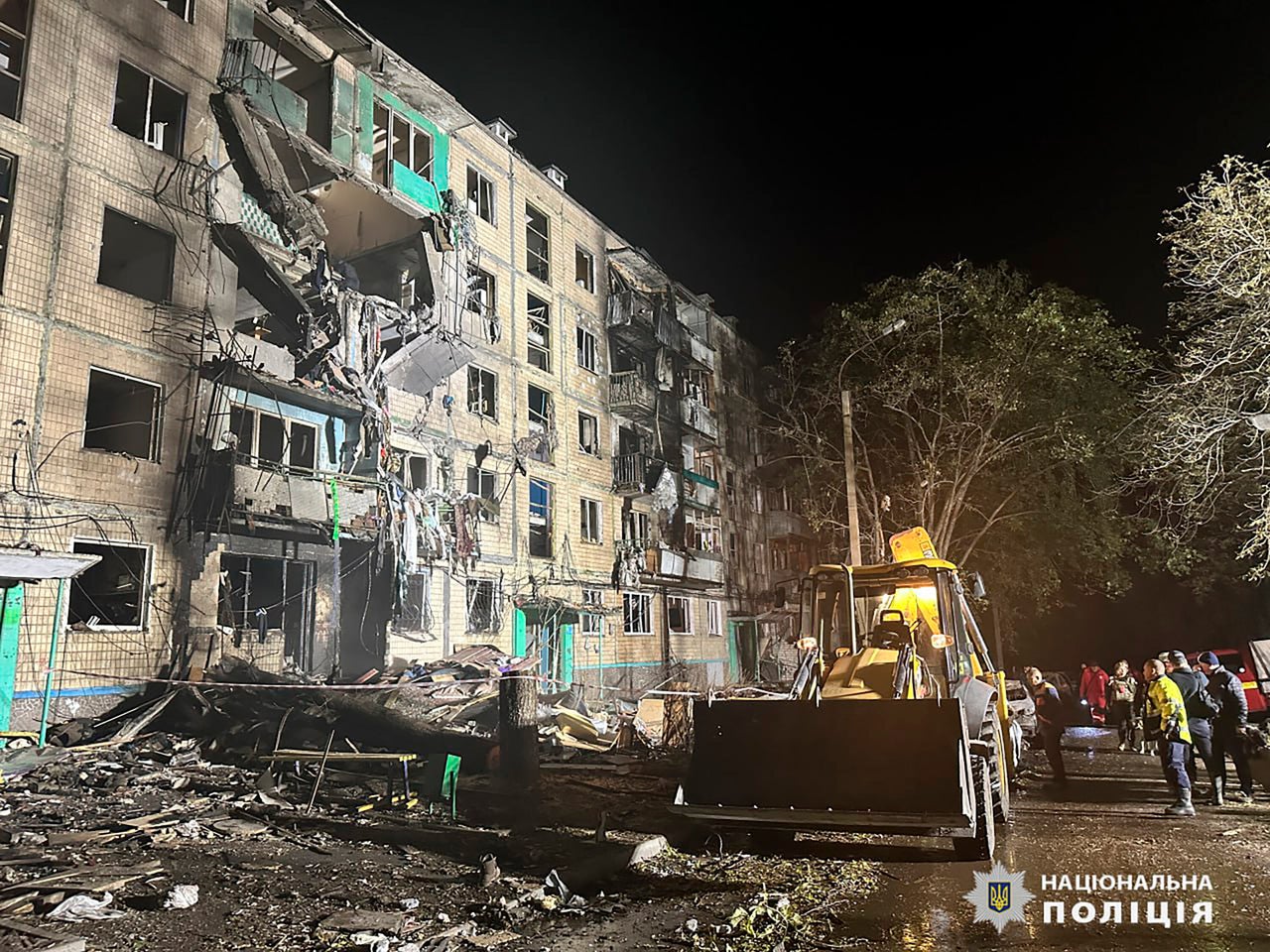 People gather around the damage and debris after a Russian strike on a residential building in Kharkiv, Ukraine, on Oct. 2.