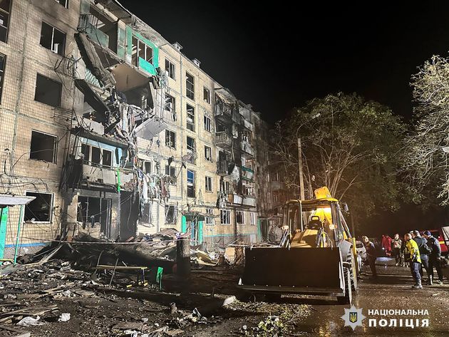 People gather around the damage and debris after a Russian strike on a residential building in Kharkiv, Ukraine, on Oct. 2.