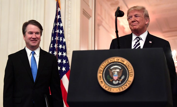 President Donald Trump smiles as he stands with Supreme Court Justice Brett Kavanaugh, whom Trump put on the nation's top court despite Kavanaugh facing credible allegations of sexually assaulting Christine Blasey Ford.