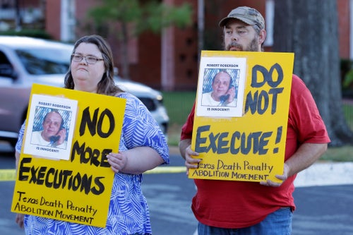 Jennifer Martin, left, and Thomas Roberson, older brother of condemned prisoner Robert Roberson, right, hold signs as they protest outside the Huntsville Unit of the Texas State Penitentiary, Oct. 17, 2024, in Huntsville, Texas.