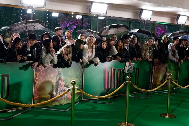 Fans stand in the rain waiting for the cast to arrive at the premiere of the film 'Wicked' on Monday, Nov. 18, 2024, in London. (Photo by Millie Turner/Invision/AP)