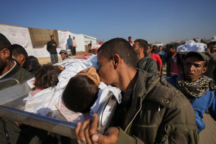 A man kisses one of three dead children being carried for burial in Khan Younis, Gaza Strip, Thursday Nov. 21, 2024. Hamza, 7, his brother Abdelaziz, 5, and his sister Laila Hassan, 4, were among nine people killed by an Israeli strike in Khan Younis on Wednesday.