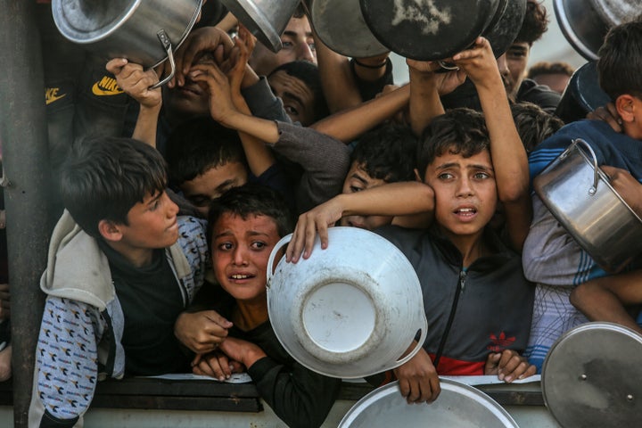 Palestinians, including children, hold metal pots and pans in a densely packed crowd as they attempt to receive food being distributed, amid relentless Israeli attacks in Khan Younis, Gaza on Nov. 22, 2024.