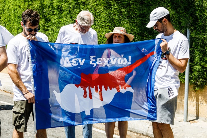 A group of Greek-Cypriots and Turkish-Cypriots is holding a bloodied Cyprus flag reading ''I don't forget,'' gathered at the Ledra Palace checkpoint to protest about the situation in Cyprus, demanding unification and peace between all communities, in Nicosia, Cyprus, on July 20, 2024. The Green Line (or buffer zone) is separating the island since 1963, as an initial measure to prevent hostilities between Greek-Cypriots and Turkish-Cypriots, but since the Turkish invasion in 1974, it is working as a de facto border between the Republic of Cyprus and the self-declared ''Turkish Republic of Northern Cyprus,'' which only Turkey recognizes as a legitimate state. (Photo by Kostas Pikoulas/NurPhoto via Getty Images)