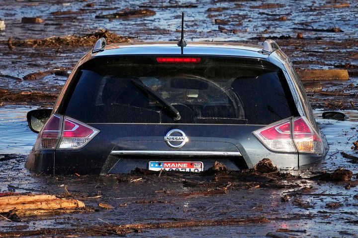 A car in a flooded parking lot by the Kennebec River in Waterville, Maine, on Dec. 19, 2023, amid unseasonably warm weather and storms.