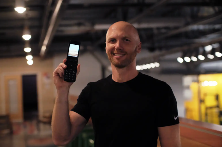 The author holds his flip phone.