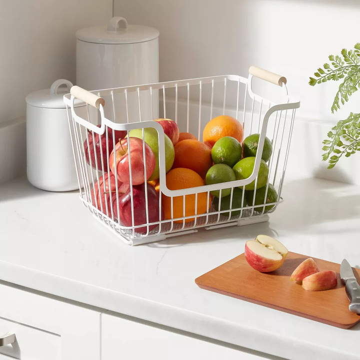 A wire stacking basket with rubberwood handles