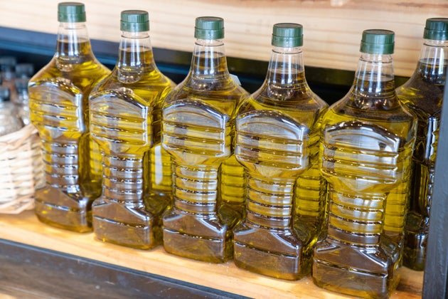Row of cooking oil cans on shelf at grocery store. Bottles with oil on grocery shop rack.