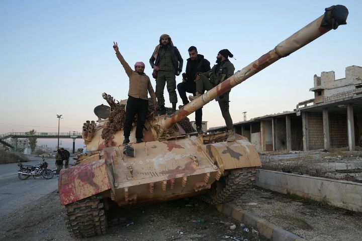 Anti-government fighters pose for a picture on a tank on the road leading to Maaret al-Numan in Syria's northwestern Idlib province on November 30, 2024. Jihadist-led rebels seized Aleppo airport and dozens of nearby towns on November 30, after overrunning most of Syria's second city of Aleppo, the Syrian Observatory for Human Rights said. (Photo by MUHAMMAD HAJ KADOUR / AFP) (Photo by MUHAMMAD HAJ KADOUR/AFP via Getty Images)