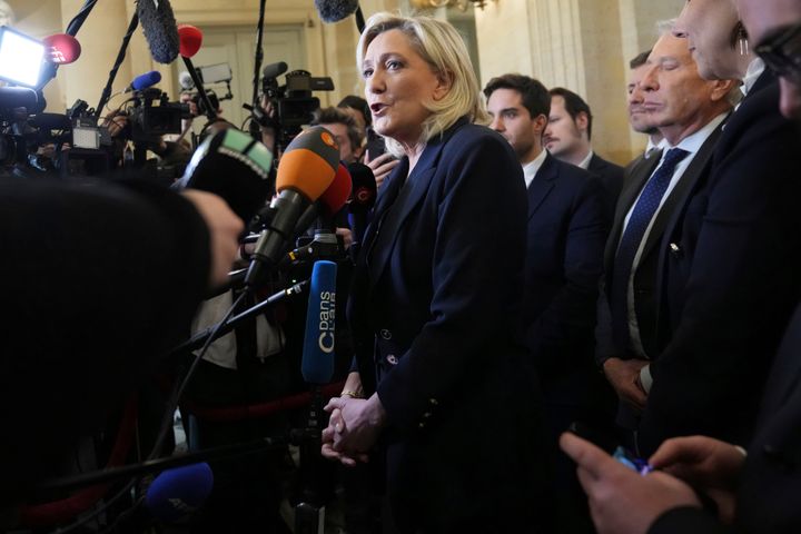 French far-right leader Marine Le Pen, center, answers reporters at the National Assembly and confirmed the National Rally party will vote against Prime Minister Michel Barnier in an upcoming no-confidence vote, Monday, Dec. 2, 2024 in Paris. (AP Photo/Michel Euler)