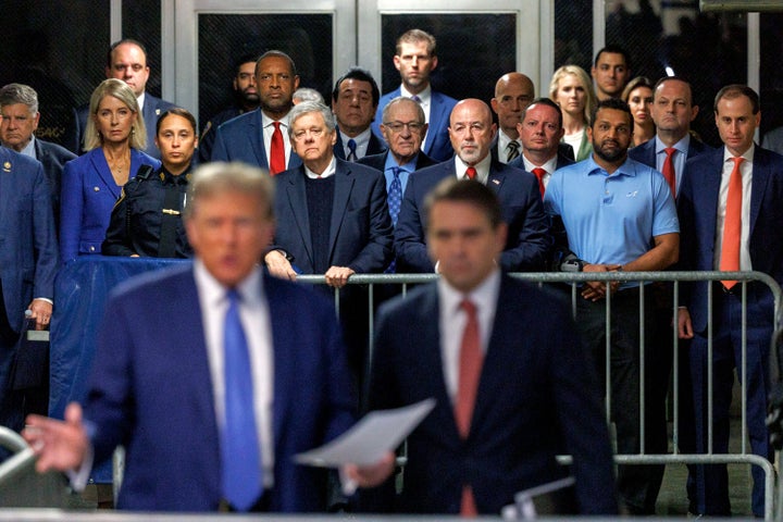 Kash Patel, in a blue shirt, watches as Donald Trump speaks to members of the media while arriving at Manhattan criminal court in New York on May 20, 2024.