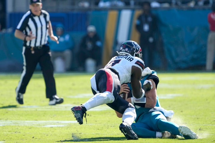 Jacksonville Jaguars quarterback Trevor Lawrence (16) slides down as Houston Texans linebacker Azeez Al-Shaair (0) charges forward during the first half of an NFL football game, Sunday, Dec. 1, 2024, in Jacksonville, Fla. Lawrence was injured on the play and Al-Shaair was ejected from the game for the unecessary hit.(AP Photo/John Raoux)