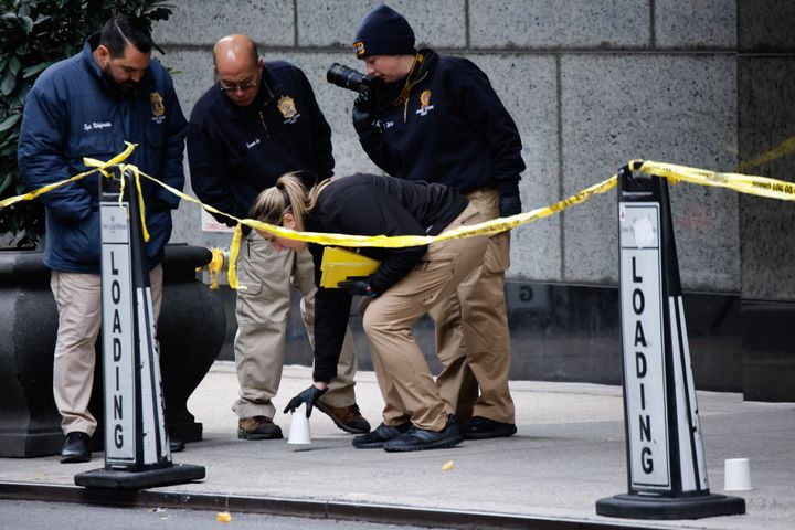 Members of the New York police crime scene unit pick up cups marking the spots where bullets lie as they investigate the scene outside the Hilton Hotel in midtown Manhattan where Brian Thompson, the CEO of UnitedHealthcare, was fatally shot Wednesday.