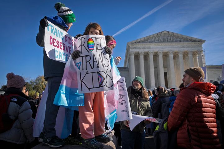 Nate, 14, left, and Bird, 9, right, whose parents asked not to use their last names, hold signs and transgender pride flags as supporters of transgender rights rally by the Supreme Court. (AP Photo/Jacquelyn Martin)