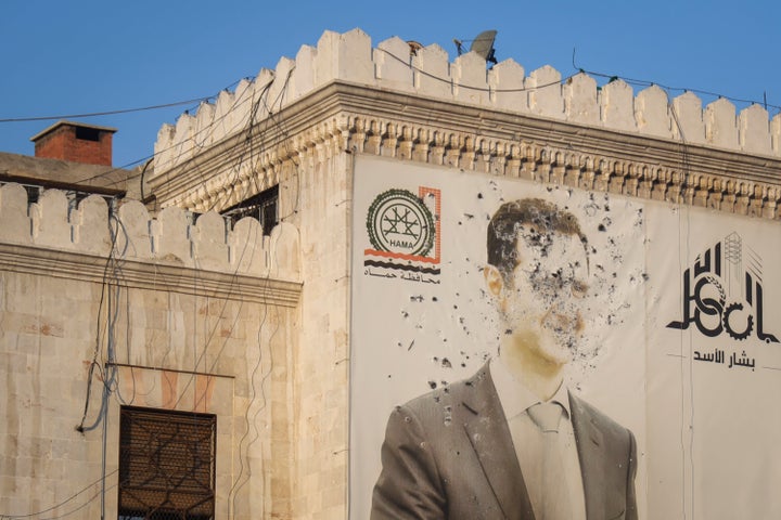 An image of Syrian President Bashar Assad, riddled with bullets, is seen on the facade of the provincial government office in the aftermath of the opposition's takeover of Hama, Syria, Friday, Dec. 6, 2024. (AP Photo/Omar Albam)