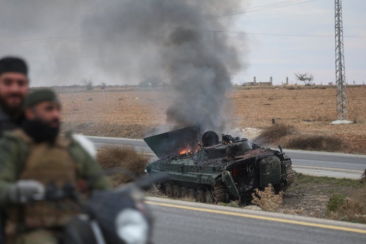 Syrian opposition fighters drive past a burning government armored vehicle south of Hama, Syria, on Saturday, Dec. 7, 2024. (AP Photo/Ghaith Alsayed)