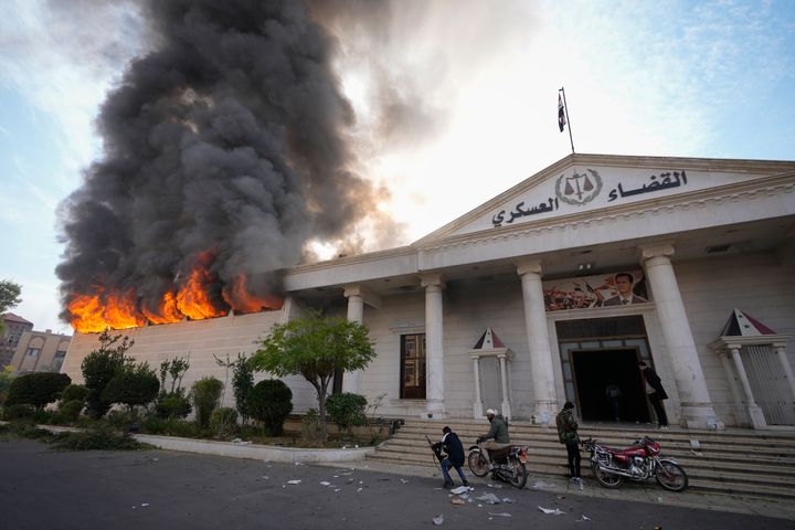 Opposition fighter burn down a military court in Damascus, Syria, Sunday Dec. 8, 2024. (AP Photo/Hussein Malla)