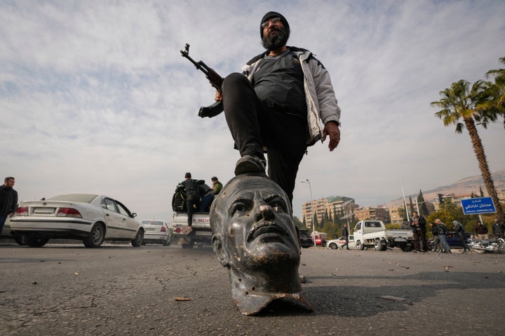 An opposition fighter steps on a broken bust of the late Syrian President Hafez Assad in Damascus, Syria, on Dec. 8, 2024.