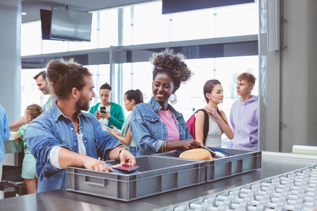 Multiracial group of passengers passing by airport security check.