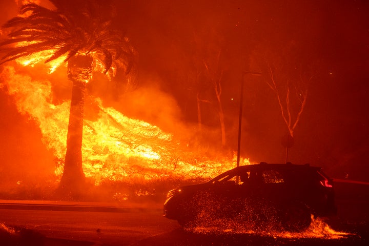 A car drives past flames from the Franklin Fire at Pepperdine University in Malibu, Calif., Tuesday, Dec. 10, 2024. (AP Photo/Eric Thayer)