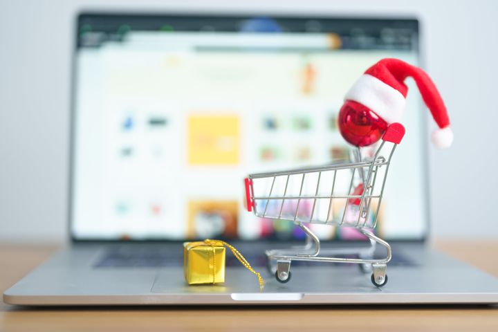 Christmas Online Shopping concept. Boxes with shopping cart on a laptop computer. Sale and discount during Christmas and New Year holiday, ecommerce, shipping delivery, logistics and Cyber Monday