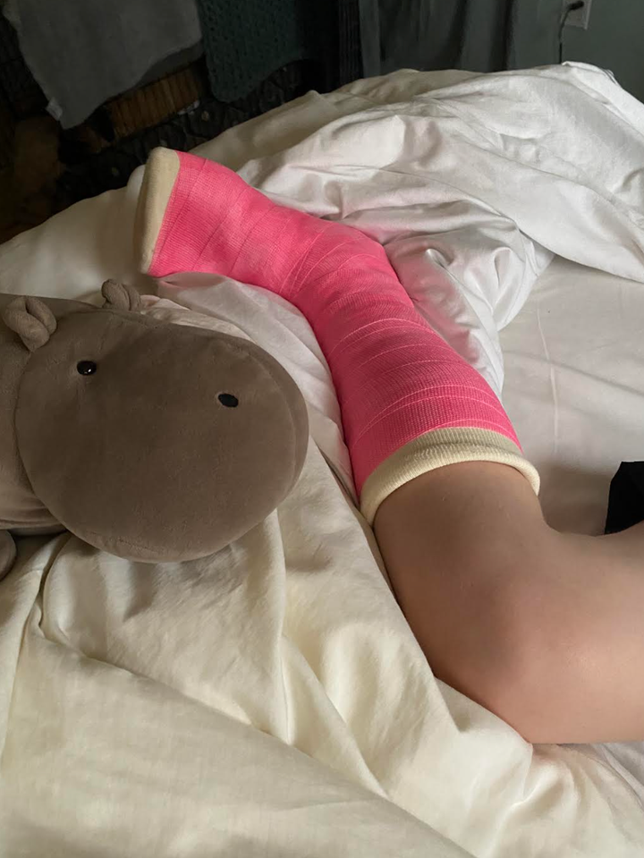 The author’s daughter lies in bed, relaxing in her pink casts, with Fiona the hippo.