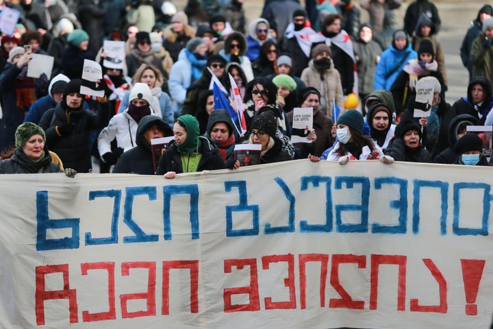 People hold a banner saying "Hands off my child" in Georgian, protesting outside of the Georgian parliament as the parliament begins the procedure of the presidential elections, in Tbilisi, Georgia, Saturday, Dec. 14, 2024. (AP Photo/Zurab Tsertsvadze)