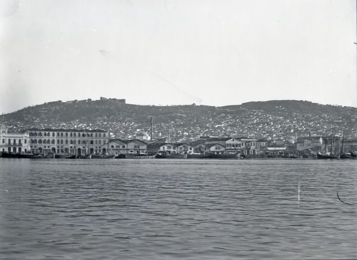 Σμύρνη, 1921-1922. Γενική άποψη της ακτογραμμής, πόλης και προκυμαίας – Quais, από την Εθνική Τράπεζα της Ελλάδος (αριστερά) ως το Τελωνείο (δεξιά). Στο βάθος διακρίνεται η ακρόπολη του Πάγου με το μεσαιωνικό κάστρο.