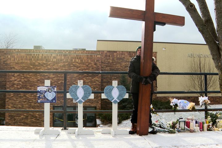 Dan Beazley stands with the homemade cross he brought from Michigan for victims of a shooting at Abundant Life Christian School on Dec. 18, 2024, in Madison, Wis. 