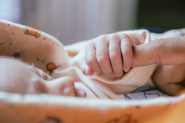 Baby holds his mother finger and sleeping