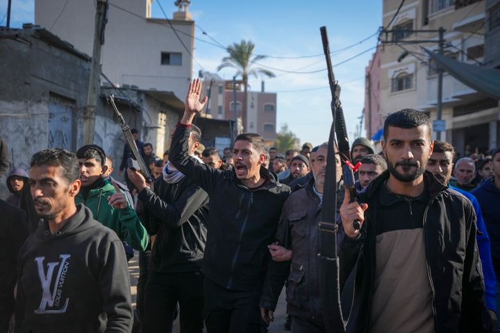 Kerabat dan tetangga, dua di antaranya memegang senjata, berjalan saat prosesi pemakaman korban serangan Israel di sebuah rumah Sabtu malam yang menewaskan sedikitnya delapan orang, di Deir al-Balah, Jalur Gaza tengah, Minggu, 22 Desember. 2024. Beberapa keluarga di Gaza dipersenjatai untuk melindungi rumah mereka dari pencuri di kamp-kamp. (Foto AP/Abdel Kareem Hana)