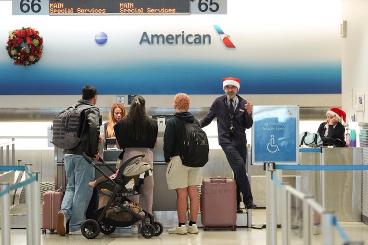 American Airlines employees, some wearing Santa Claus hats, check in travelers in the American terminal at Miami International Airport, on Christmas Eve, Tuesday, Dec. 24, 2024, in Miami. (AP Photo/Rebecca Blackwell)