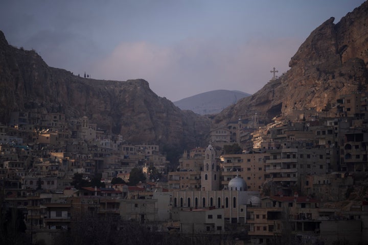 Σπίτια φαίνονται κατά μήκος του βουνού καθώς ένας σταυρός στέκεται πάνω από το ελληνορθόδοξο μοναστήρι της Αγίας Θέκλας την παραμονή των Χριστουγέννων στη Μαλούλα , περίπου 60 χιλιόμετρα βόρεια της Δαμασκού, Συρία, Τρίτη 24 Δεκεμβρίου 2024. (AP Photo/Leo Correa)