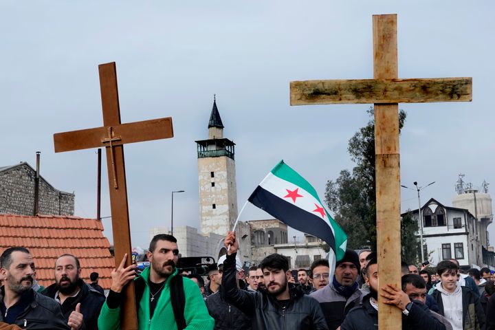 Σύροι χριστιανοί κρατούν σταυρούς και φωνάζουν συνθήματα, καθώς διαδηλώνουν κατά τη διάρκεια διαμαρτυρίας μετά την πυρπόληση χριστουγεννιάτικου δέντρου στην πόλη Χαμάχ την Κυριακή, στη Δαμασκό της Συρίας, Τρίτη 24 Δεκεμβρίου 2024 (AP Photo/Hussein Malla).