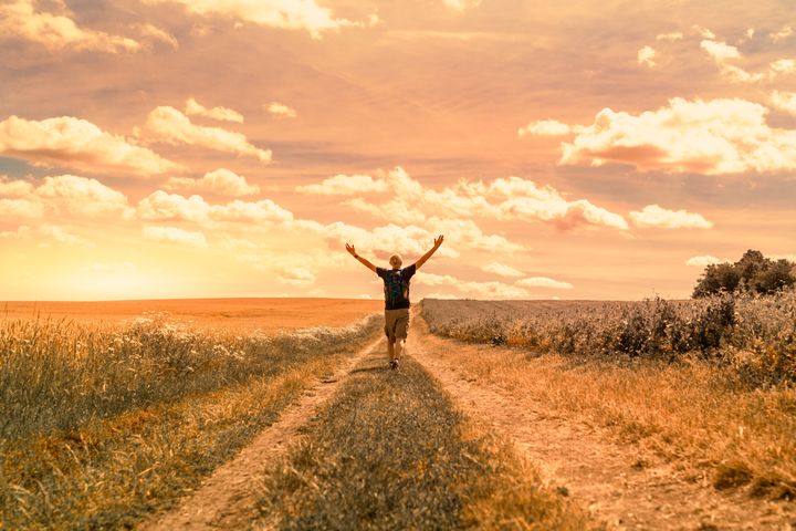 Man walking on country road on sunny warm summer day.