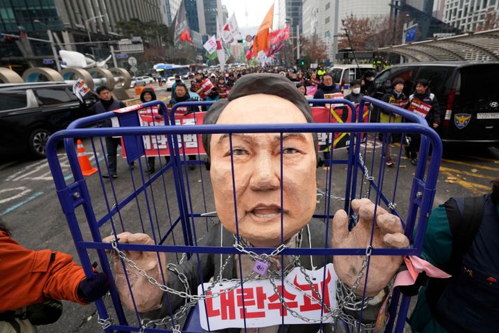 Protesters carry a caricature of impeached South Korean President Yoon Suk Yeol during a rally demanding his arrest in Seoul, South Korea, Saturday, Dec. 21, 2024. The sign, front, reads, "Rebellion leader."