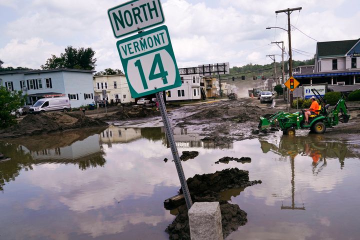 A small tractor clears water from a business as flood waters block a street, July 12, 2023, in Barre, Vt. (AP Photo/Charles Krupa, File)