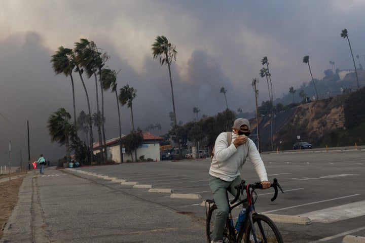 A resident rides through smoke from a brush fire pushed by gusting Santa Ana winds.