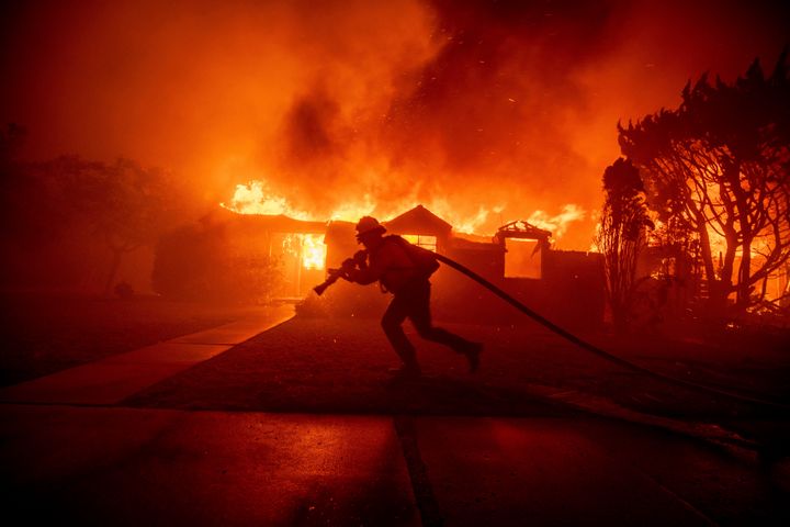 A firefighter battles the Palisades Fire as it burns a structure in the Pacific Palisades neighborhood of Los Angeles. 