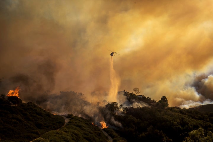 Water is dropped on the advancing Palisades Fire by helicopter.