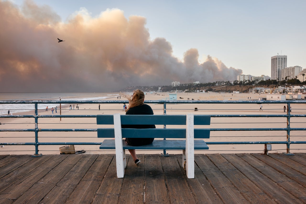 The Palisades Fire burns in the distance from the Santa Monica Pier in Santa Monica on Tuesday.