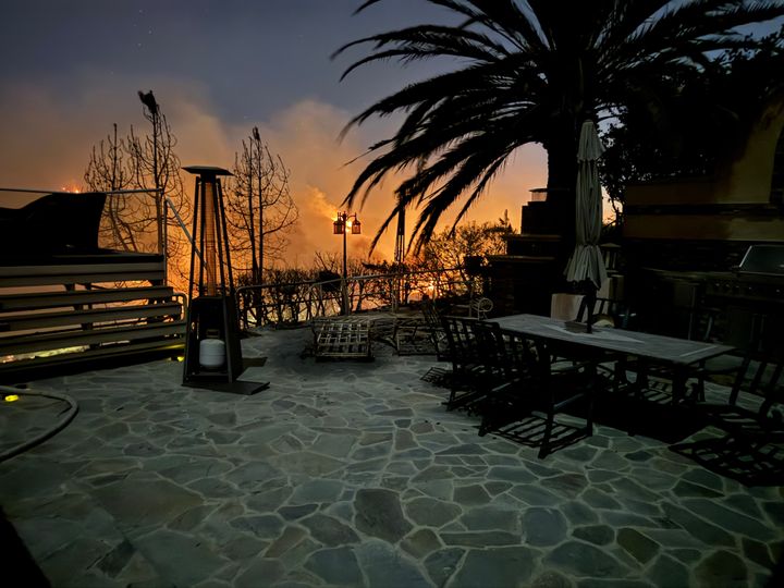 The Gollings' Palisades Highlands backyard shows the sharp glow of flames illuminating the hillside on Wednesday night.